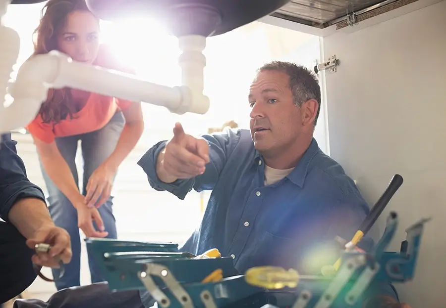 Plumber working under sink